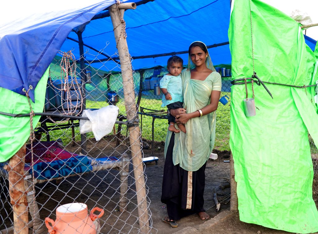 A mother and her daughter outside of their makeshift home/tent.